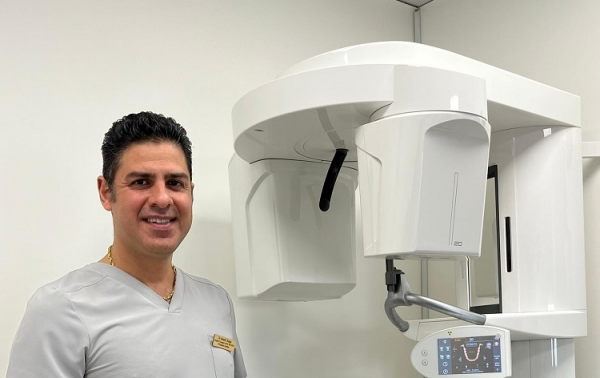 Dr Masih Sage beside the Cone Beam CT scanner at Green Lane Dental Centre in Penge