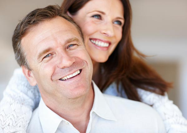 Smiling middle-aged couple after implant-supported denture treatment